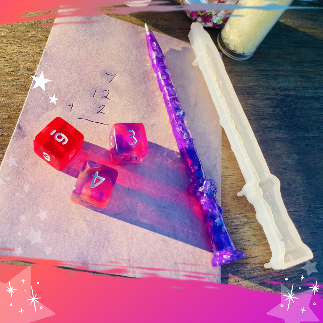 On a brown table sits 3 red dice on pink construction paper with a purple wand and other magical tools.