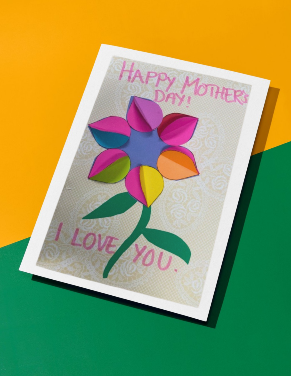 Handmade card with decorative paper and colorful paper cutouts in the shape of a flower.
