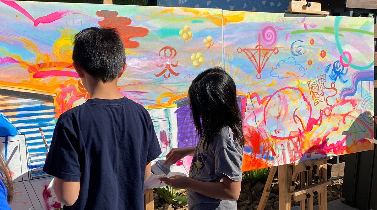 Photo of two kids painting a canvas