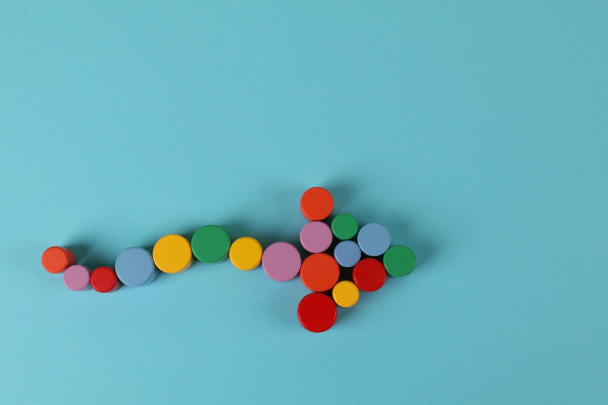 An arrow formed by multiple-colored circles on a light blue background.