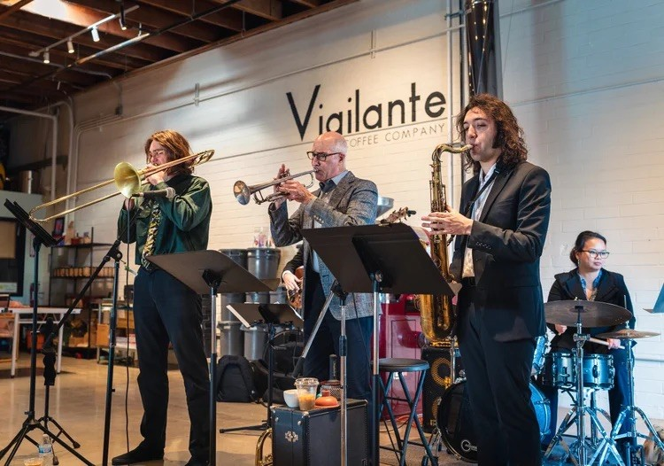 Image of four of the Soto Six musicians on stage playing brass instruments and drums
