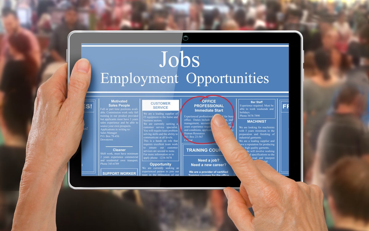 two hands are holding a tablet and looking at a blue screen viewing job opportunities.  