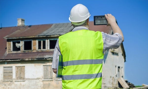 Building inspector taking pictures of an old abandoned building