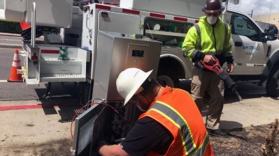 City electricians working on a panel on the side of a street