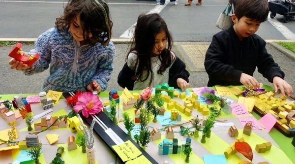 Children placing blocks and decorations on a pretend city.