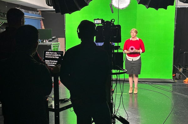 Behind the scenes of video crew and person in front of green screen