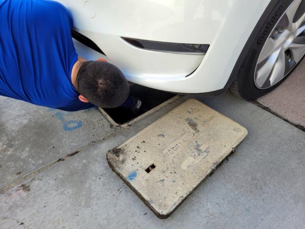 Code enforcement employee accessing a meter under a car