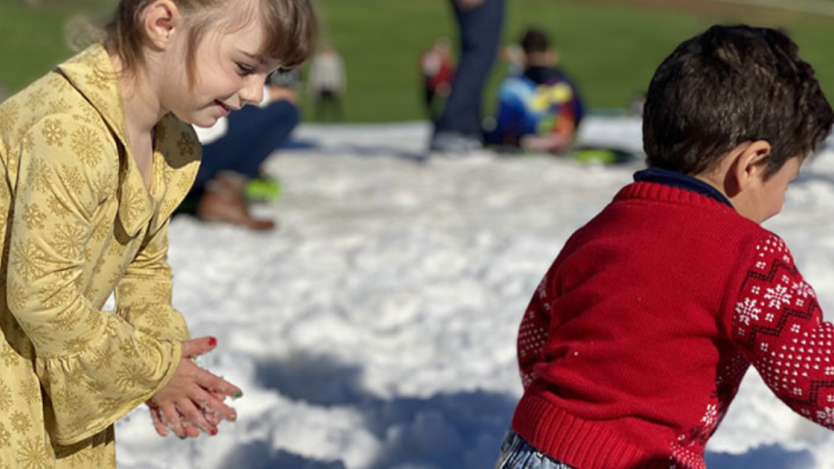 two children playing in snow at a Parks & Recreation winter festival