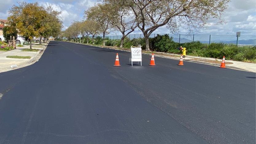 road in Otay Mesa with new overlay treatment; road has cones lined up to block traffic