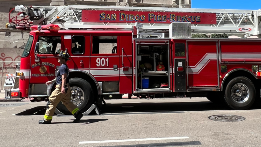 side view of a fire truck with a firefighter walking by