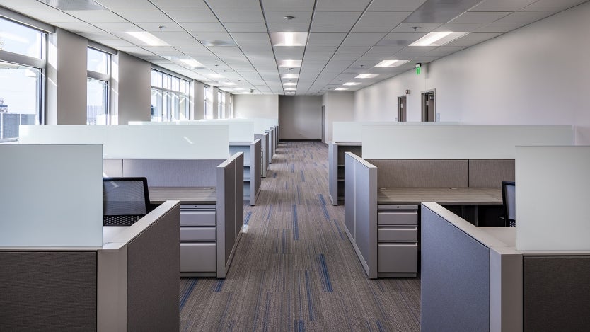 inside of an office with the aisle down the middle and two rows of cubicles lined up