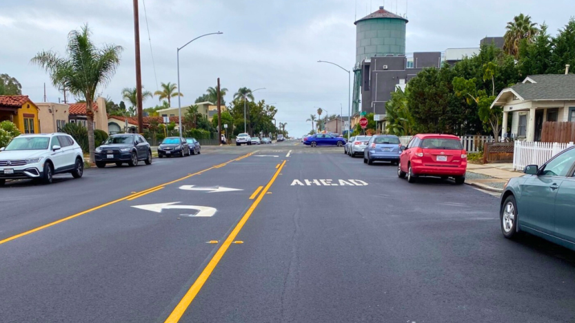 Newly slurry sealed road surrounded by parked cars