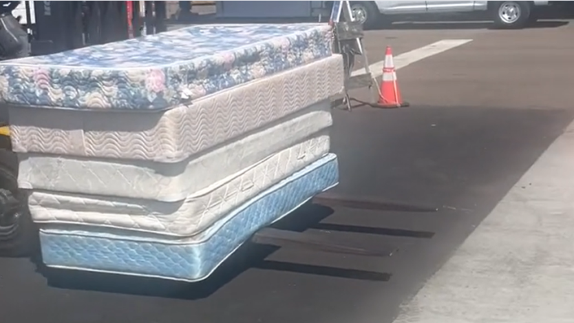 five mattresses stacked being carried to truck