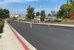 Freshly repaired and resurfaced road with traffic cones in the center