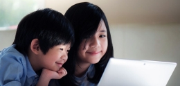Two Asian children looking at a laptop monitor