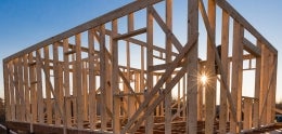 The wooden frame of an Accessory Dwelling Unit in construction with the sun in the background. 