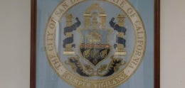 Embroidered cross-striched seal in gold&#44; blue&#44; and white on sky blue background. 