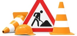 Construction cones, hard hat and a sign showing construction work.