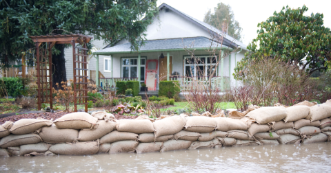 front view of a one-story house with sandbags in front of it to prevent water from flooding the house