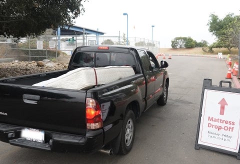 A truck carrying a mattress entering a drop-off site