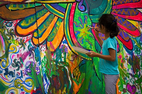 Young girl painting a mural on a wall