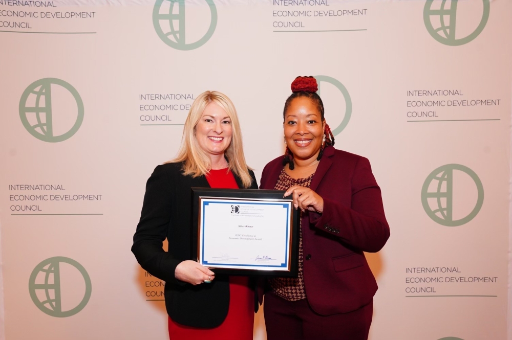 Two city employees holding award