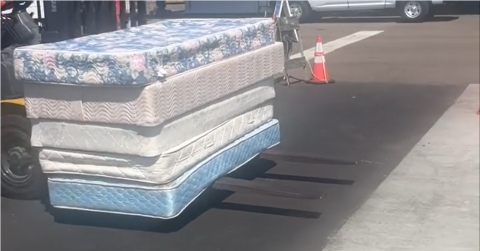 five mattresses stacked being carried to truck