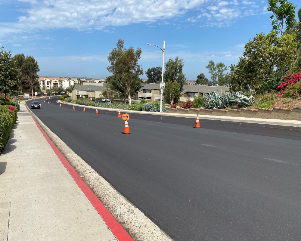 Freshly repaired and resurfaced road with traffic cones in the center