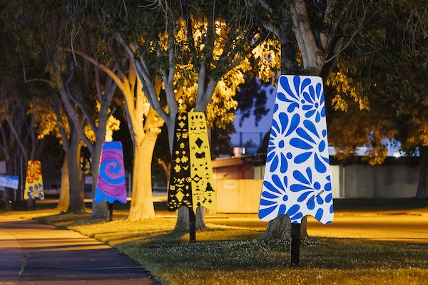 Colorful artistic sculptures shaped like popsicles displayed at a park at night