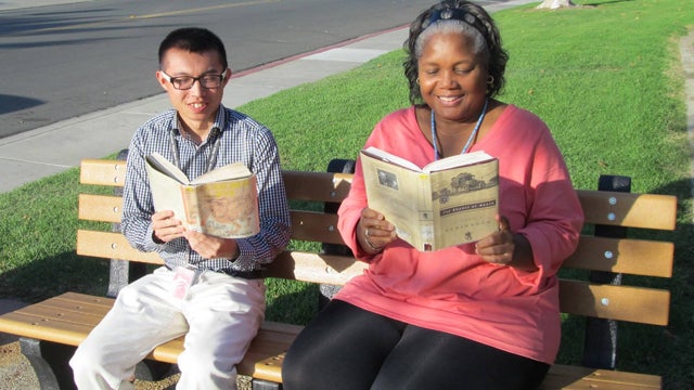 Library patrons reading books in front of the library