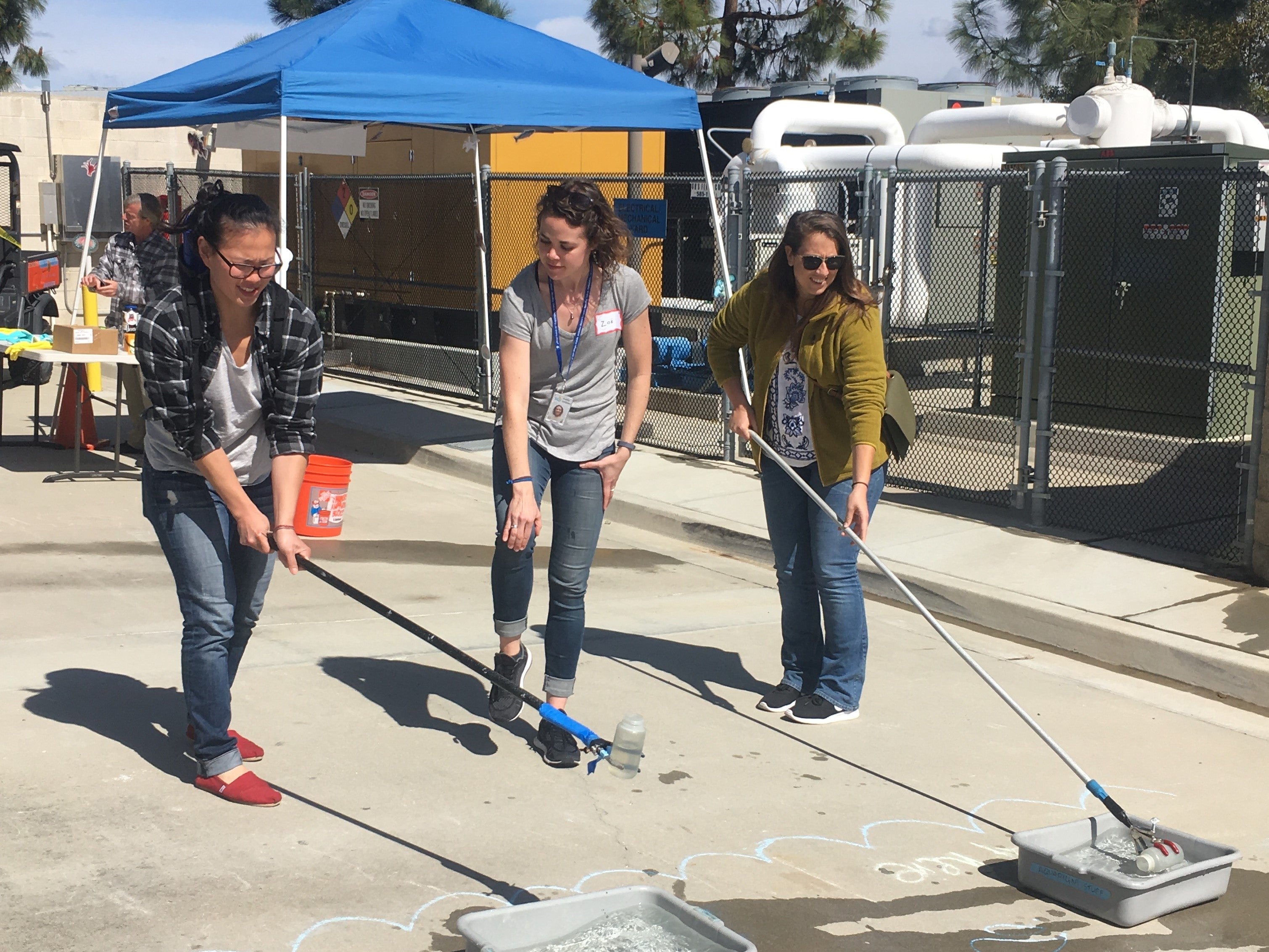 A marine biologist shows two members of the public how to conduct shoreline water quality sampling in a game.